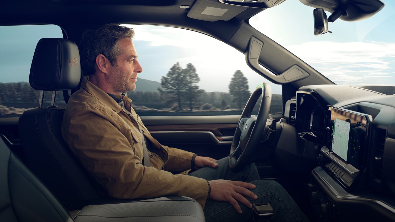 Passenger Seat View of a Man Driving a GM Vehicle Utilizing Super Cruise Hands-Free Technology 